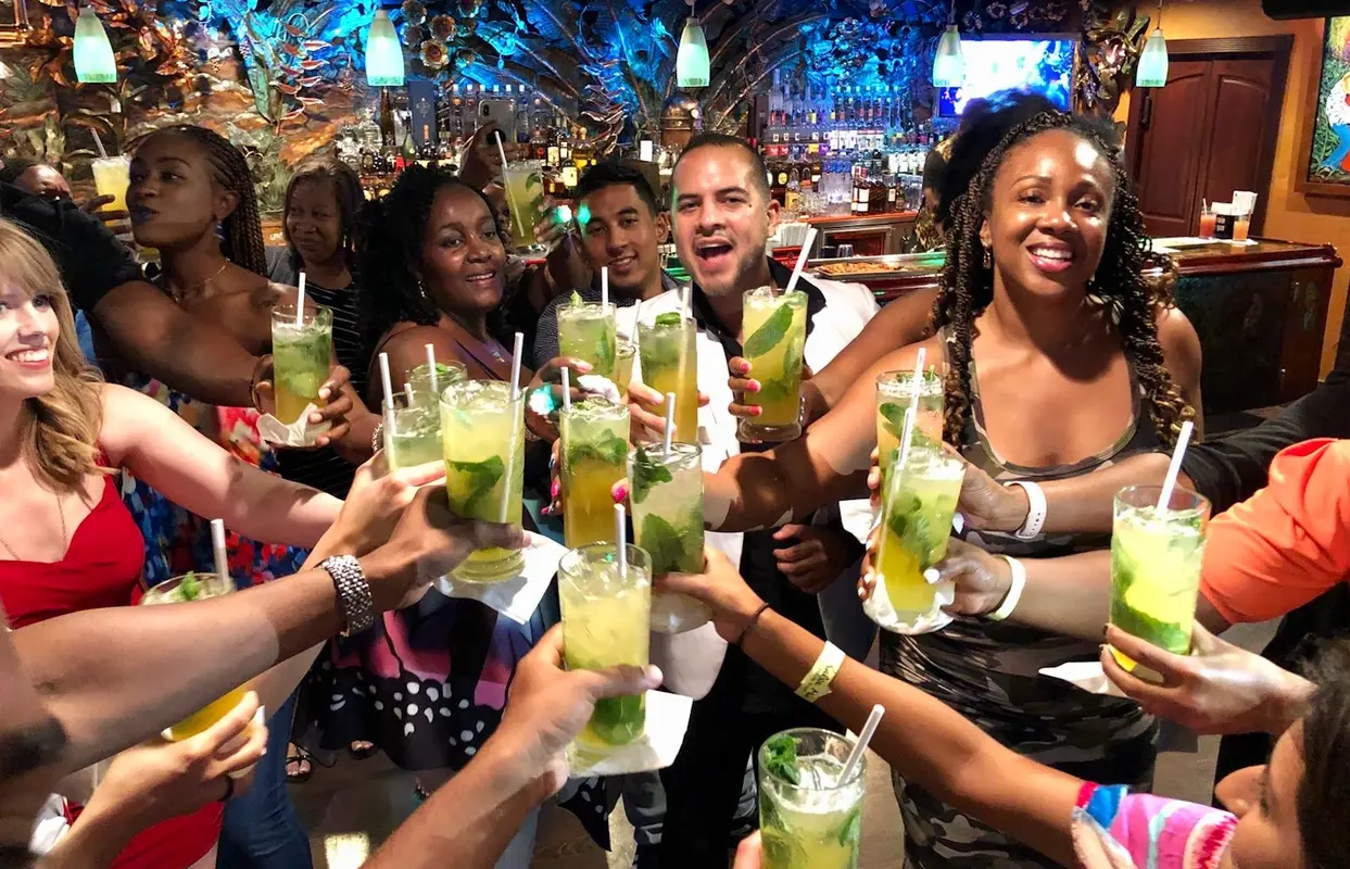 A group raising mojito glasses inside a colorful tropical club