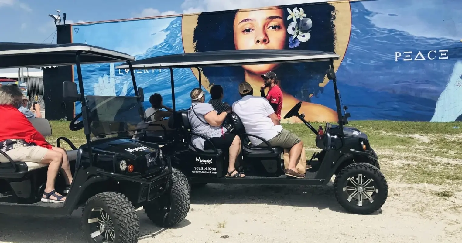A golf cart group beside a large portrait mural