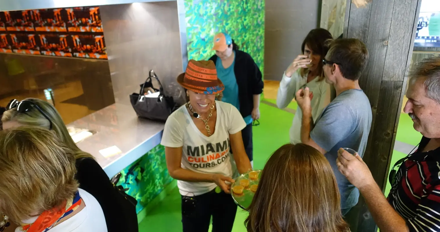 A guide in a Miami Culinary Tours shirt serving a tasting to guests
