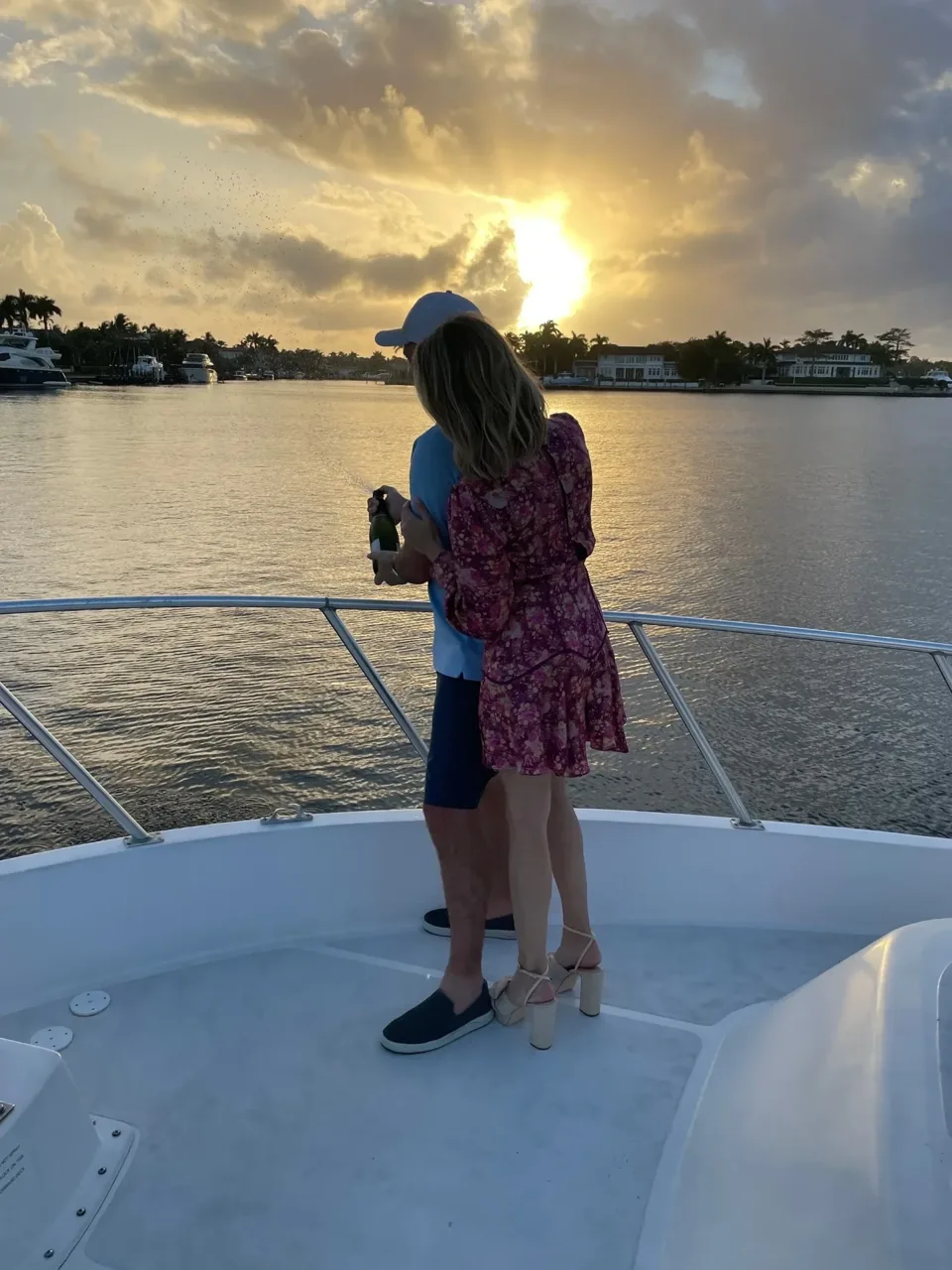 Two passengers standing on a yacht bow at sunset