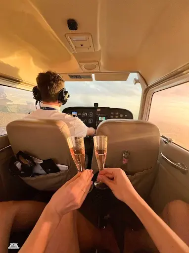 Passengers toasting behind the pilot in a Cessna cabin at sunset