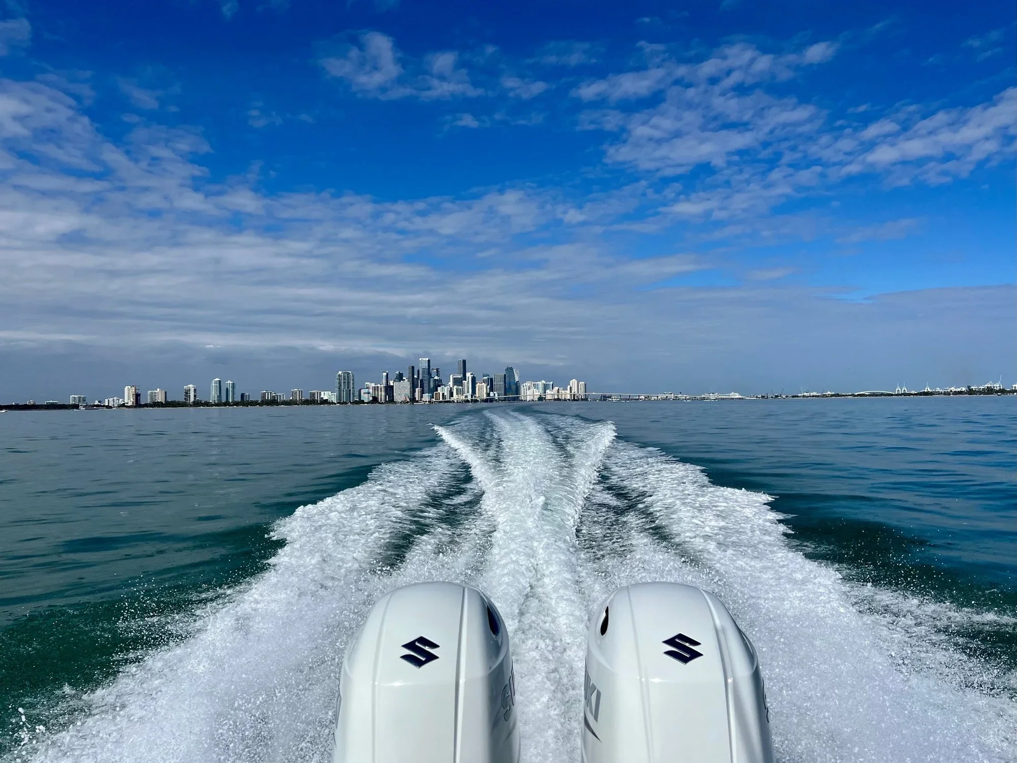Boat wake trailing toward the Miami skyline across the bay