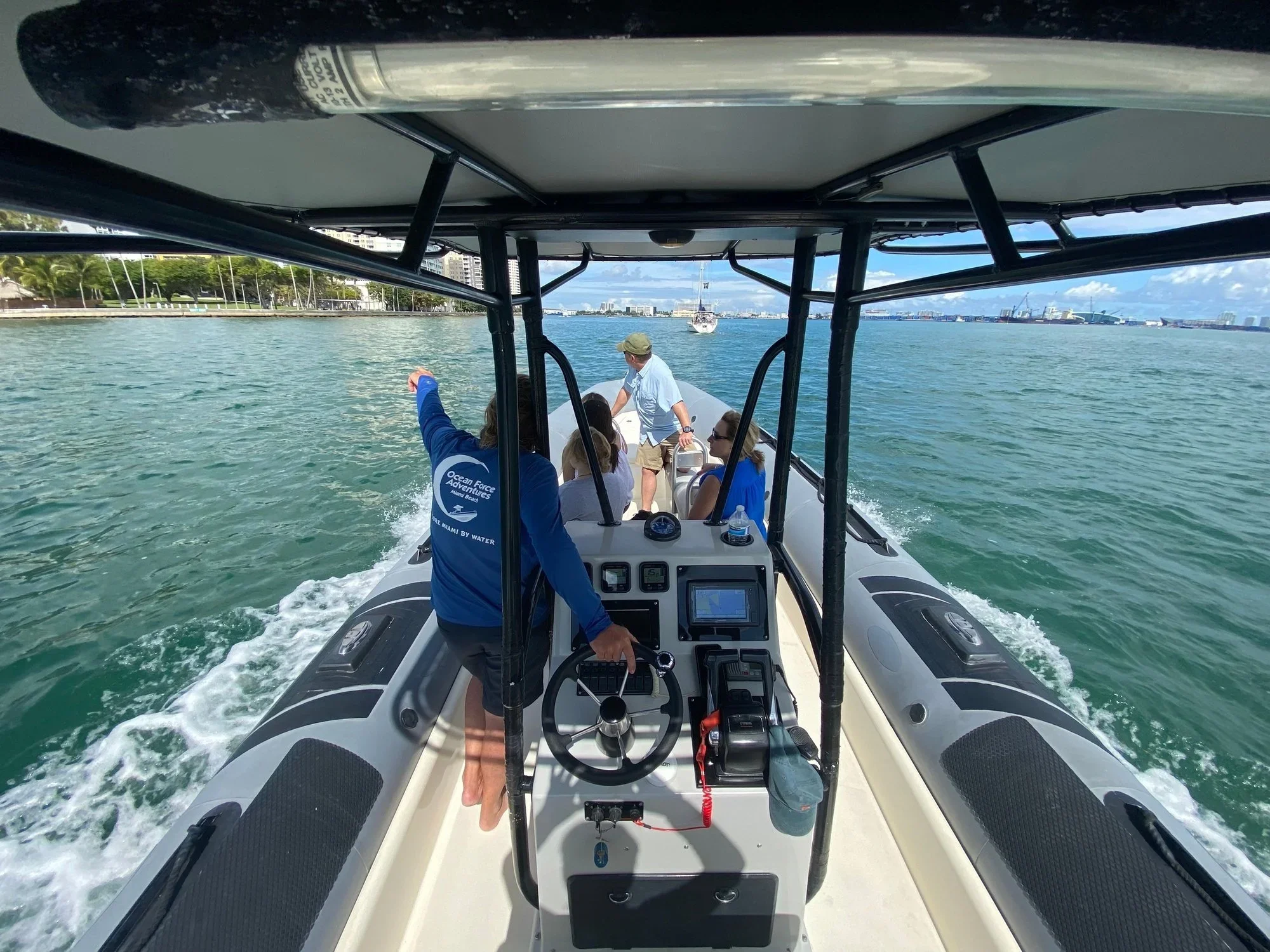 A captain steering a boat with passengers across green bay water