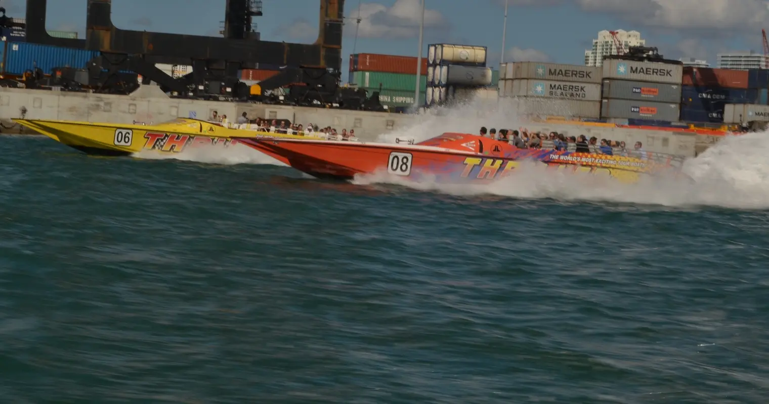 Two Thriller speedboats speeding past shipping containers