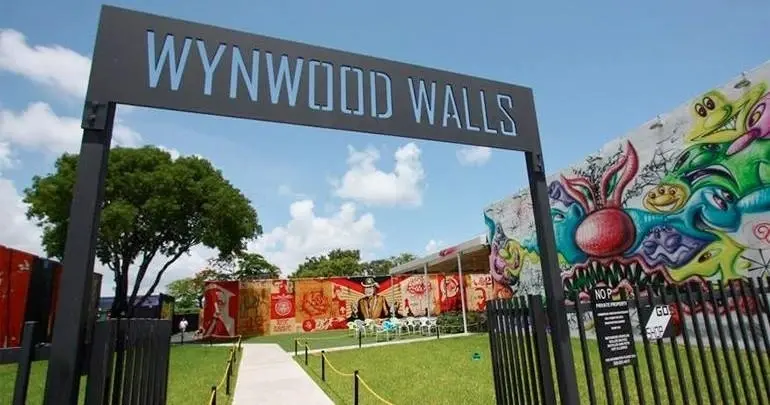 The Wynwood Walls entrance sign with murals behind it