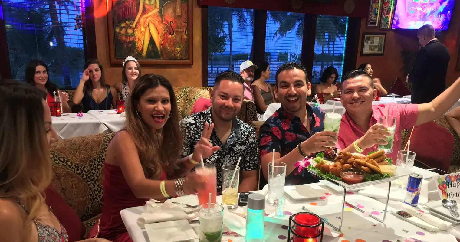 Guests smiling at a dinner table during a salsa night