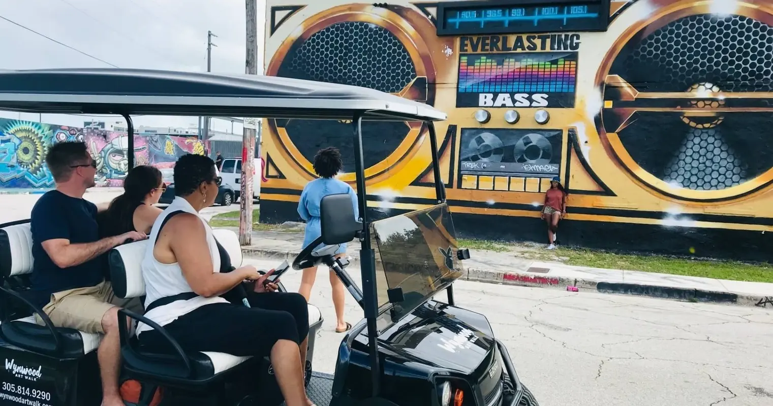 A golf cart stopped in front of a boombox mural