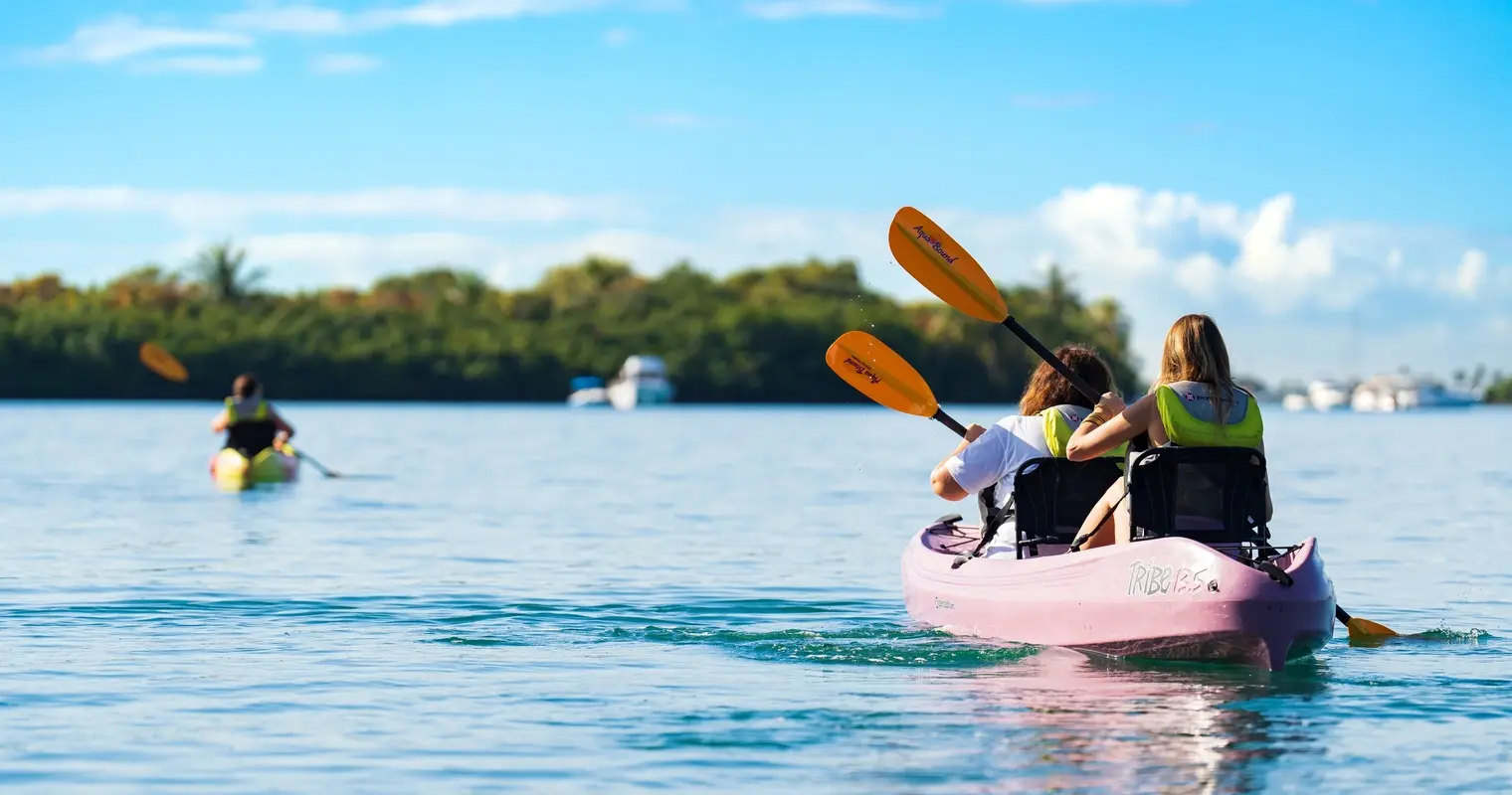 Two people paddling a pink tandem kayak on open water
