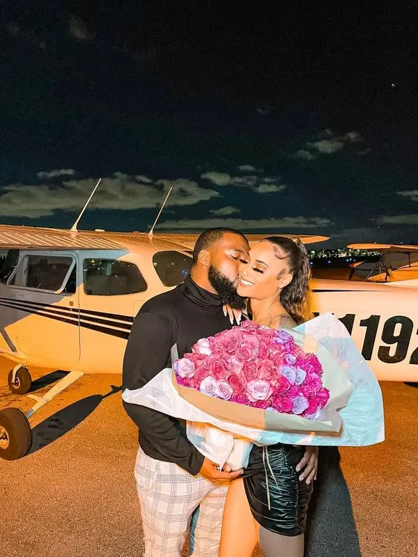 A couple with flowers beside a Cessna on the tarmac at night