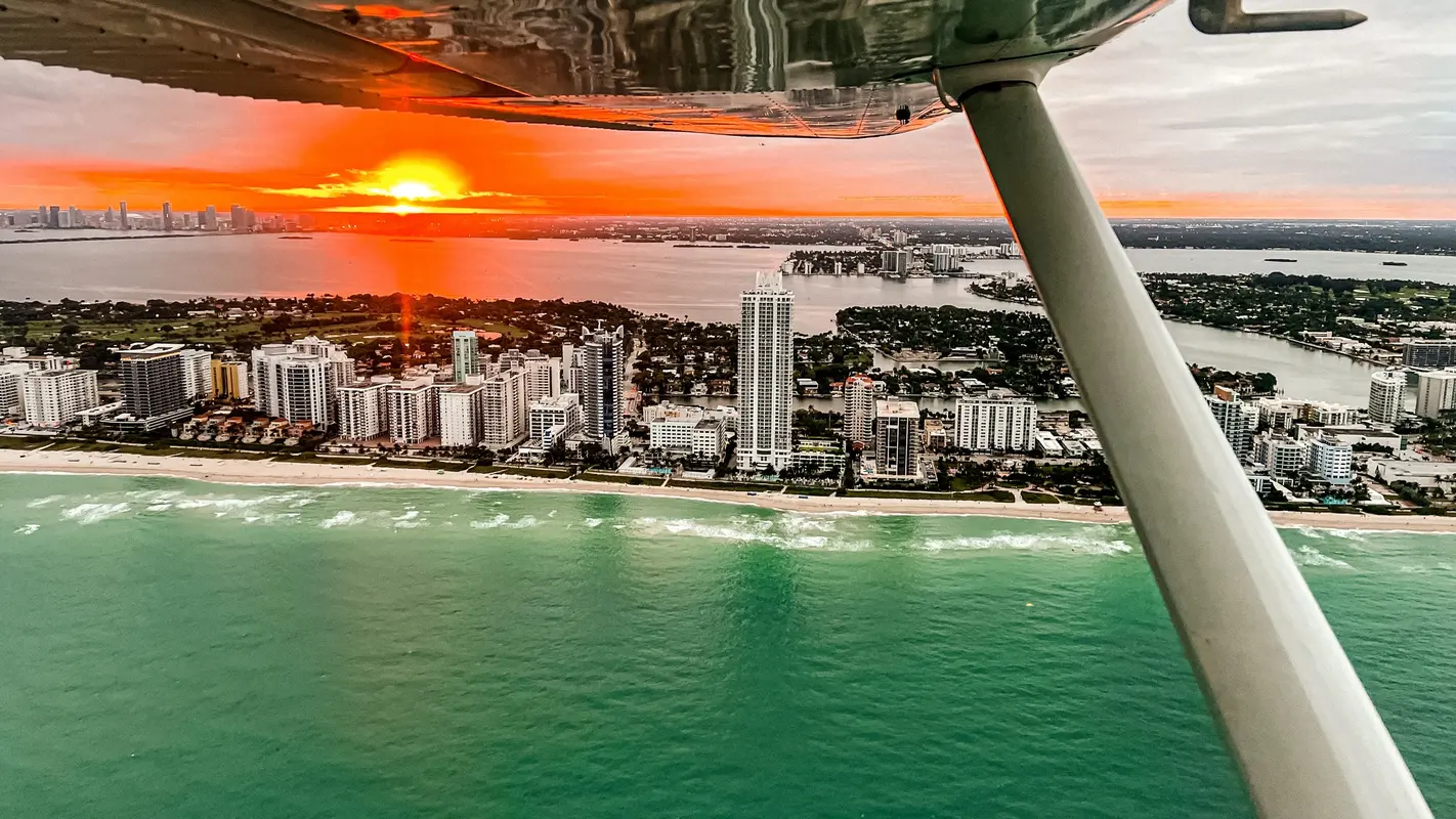 The sun setting over Miami Beach seen beneath an airplane wing