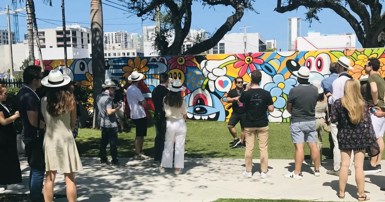 A guide speaking to a group beside a colorful cartoon mural