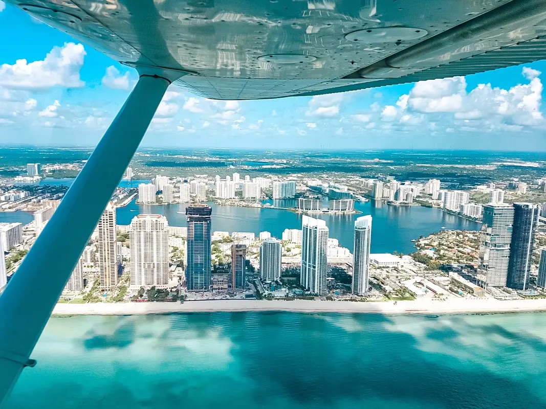 Miami Beach high-rises and turquoise water seen under a Cessna wing