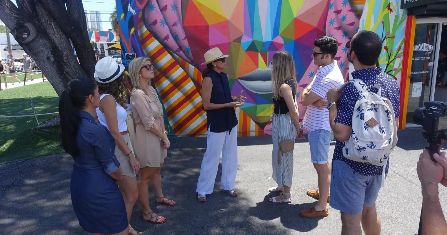 A tour group listening to a guide beside a colorful Wynwood mural