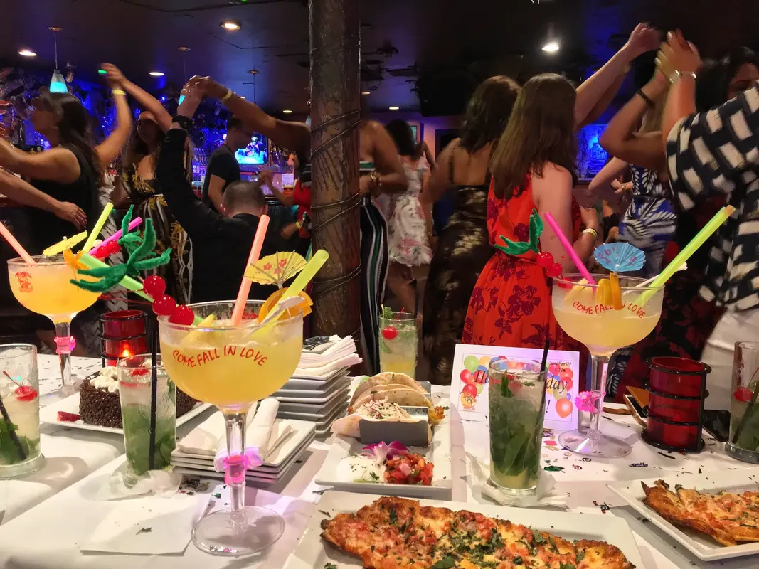 Dancers on a club floor behind a table of cocktails and appetizers