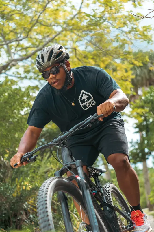 A rider in a helmet riding a mountain bike under trees