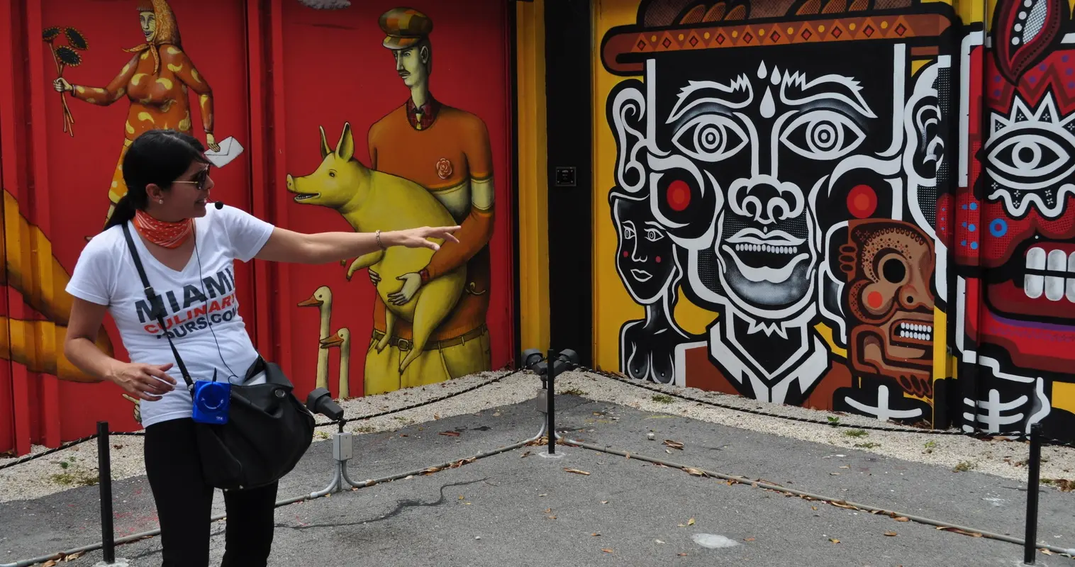 A guide pointing to a red mural wall in Wynwood
