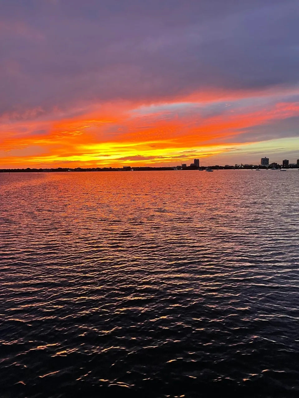 Orange sunset sky above the waterfront and rippling bay water
