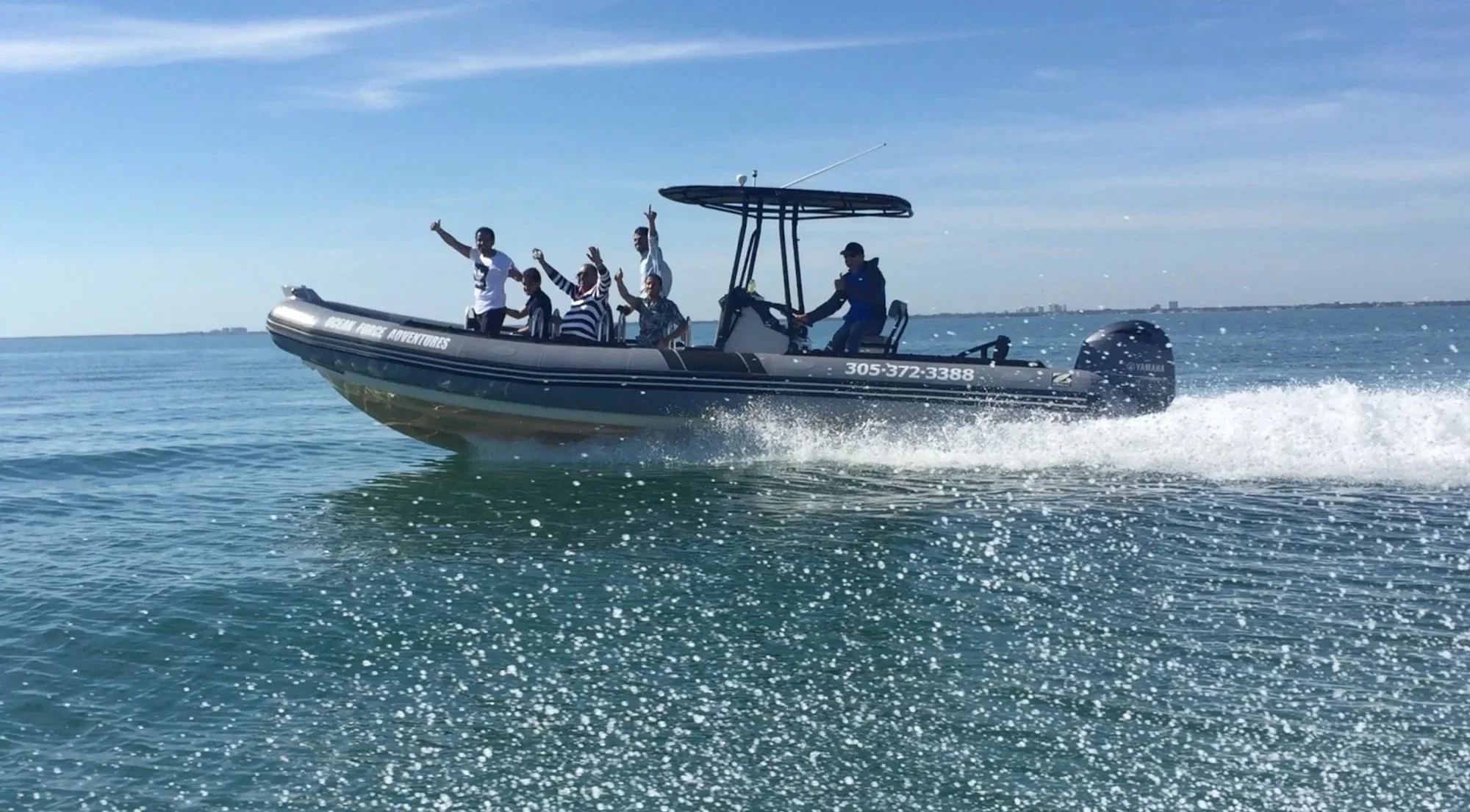 Passengers waving from a speeding Ocean Force Adventures boat
