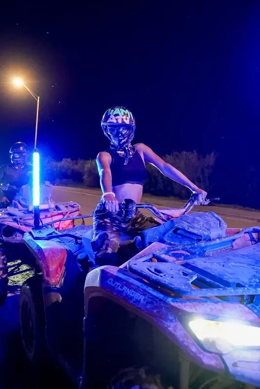 A rider in a helmet on an ATV lit by blue lights at night