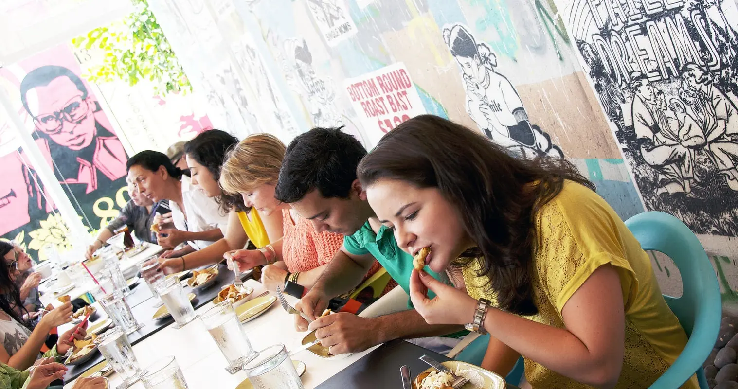 Guests tasting food at a long table under Wynwood murals