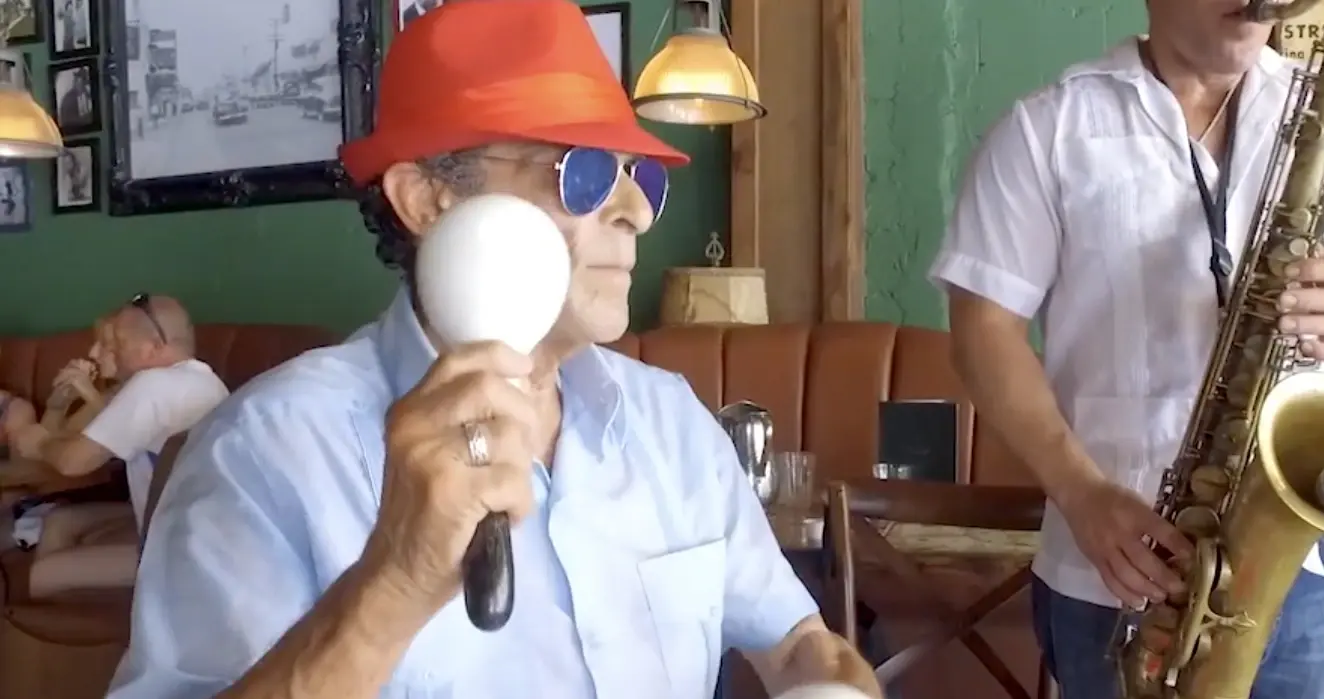 A musician with maracas beside a saxophone player in a Little Havana café