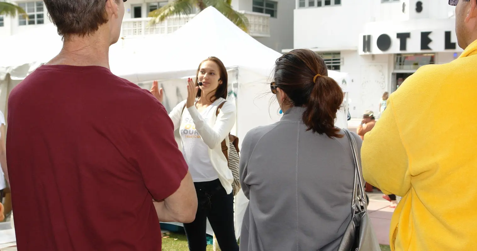A guide speaking to a group outside an Art Deco hotel