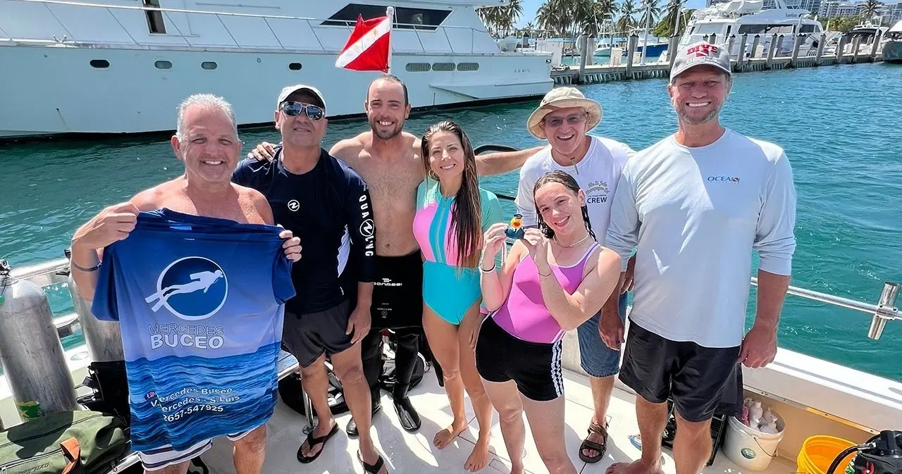 A group of divers smiling on a dive boat at the marina