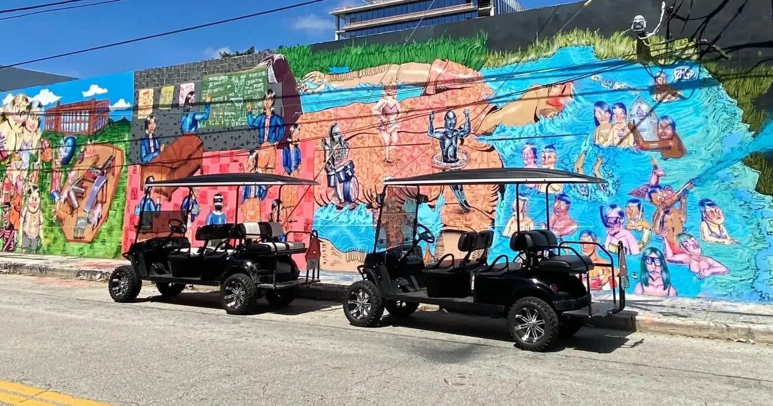 Two golf carts parked beside a long painted mural