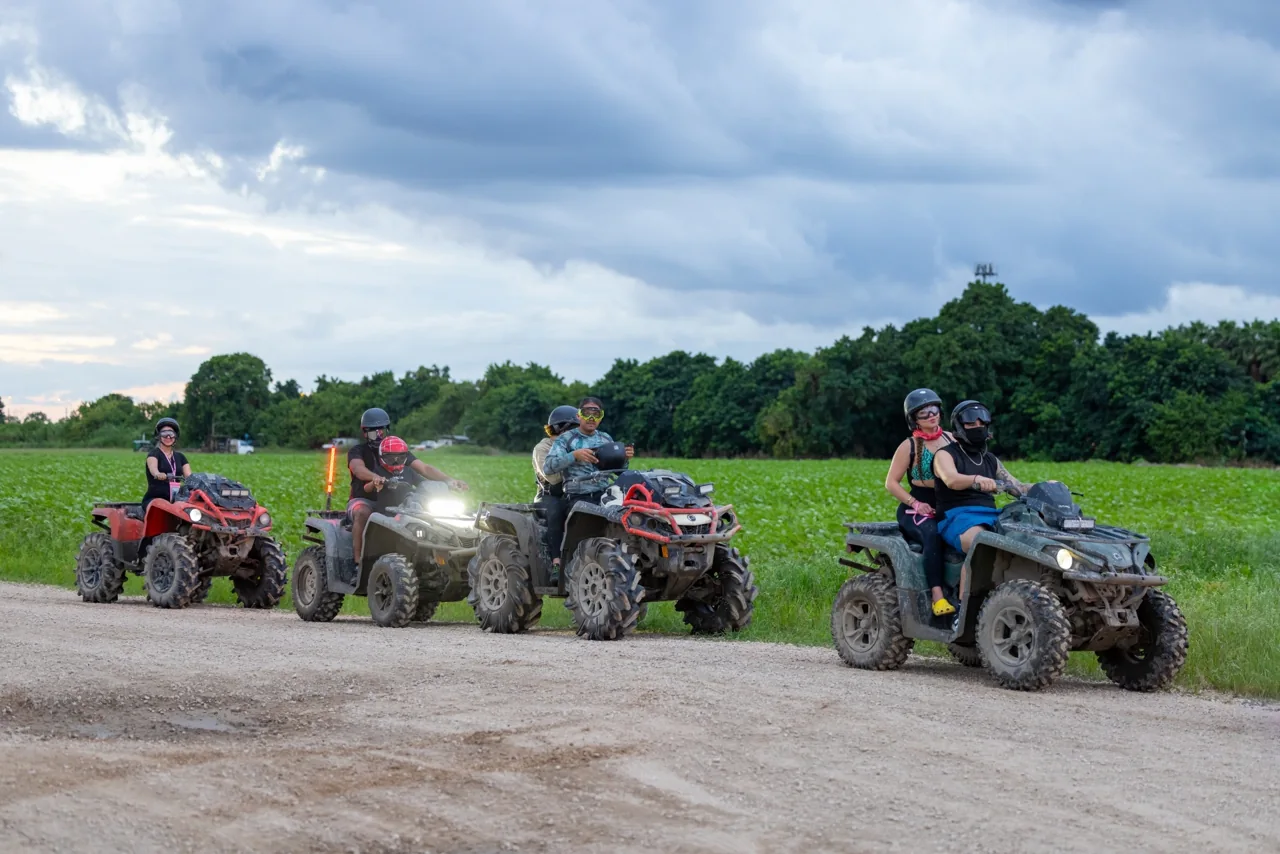 ATV riders gathered beside a field under cloudy skies