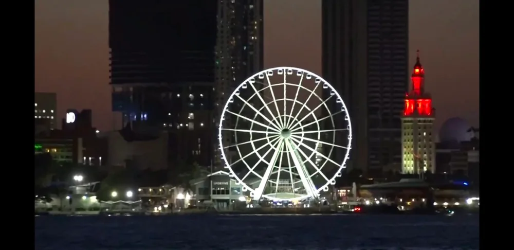 An illuminated observation wheel beside the Miami waterfront at night