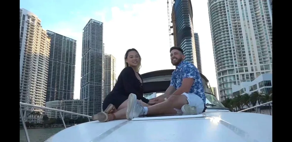Two passengers seated on a boat beside waterfront high-rises