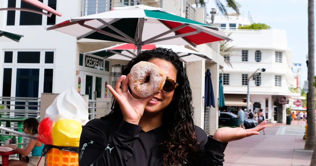 A visitor holding a donut outside a café