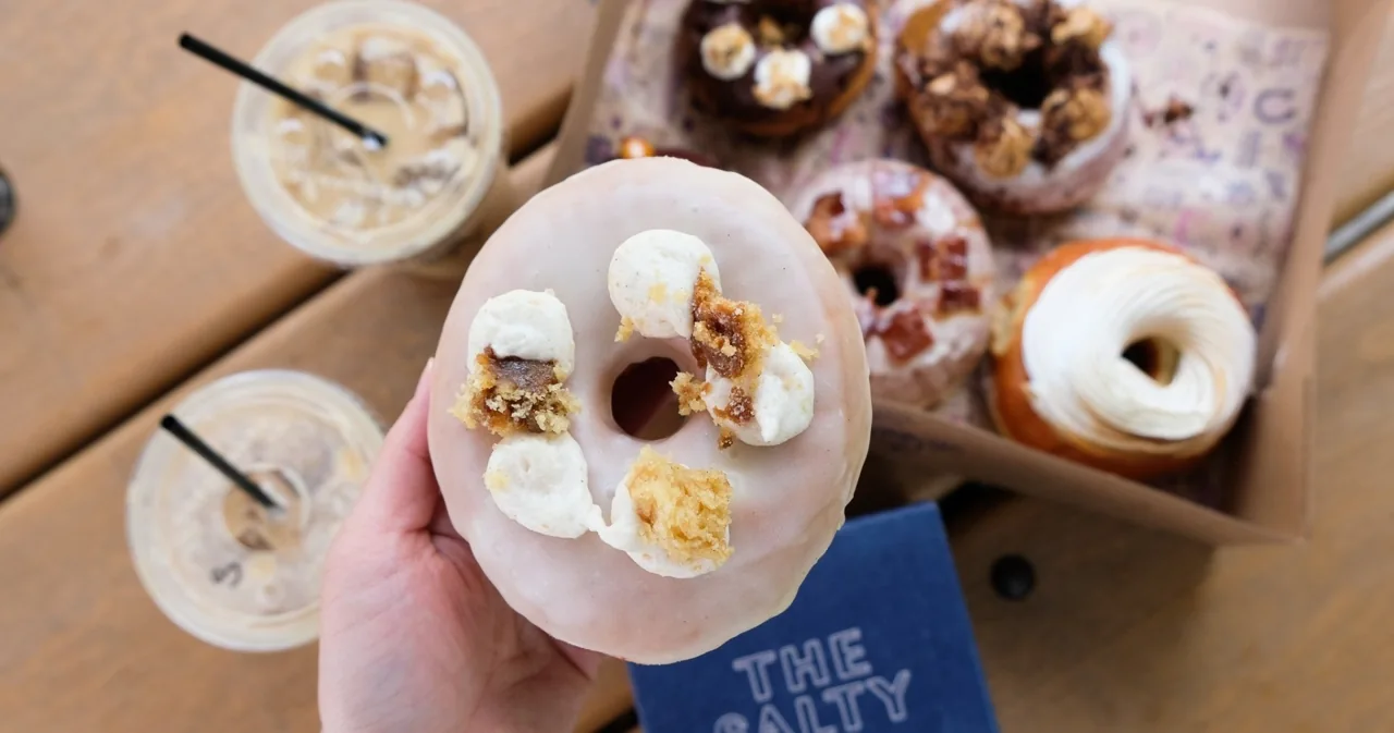 A person holding an assorted donut box above a table