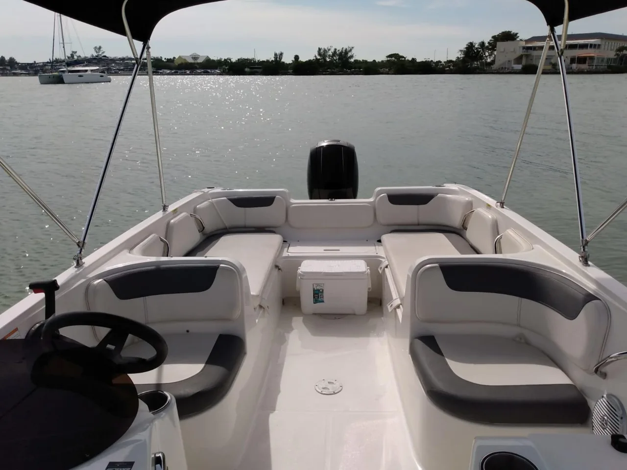 Passenger seating and steering console beneath a boat canopy