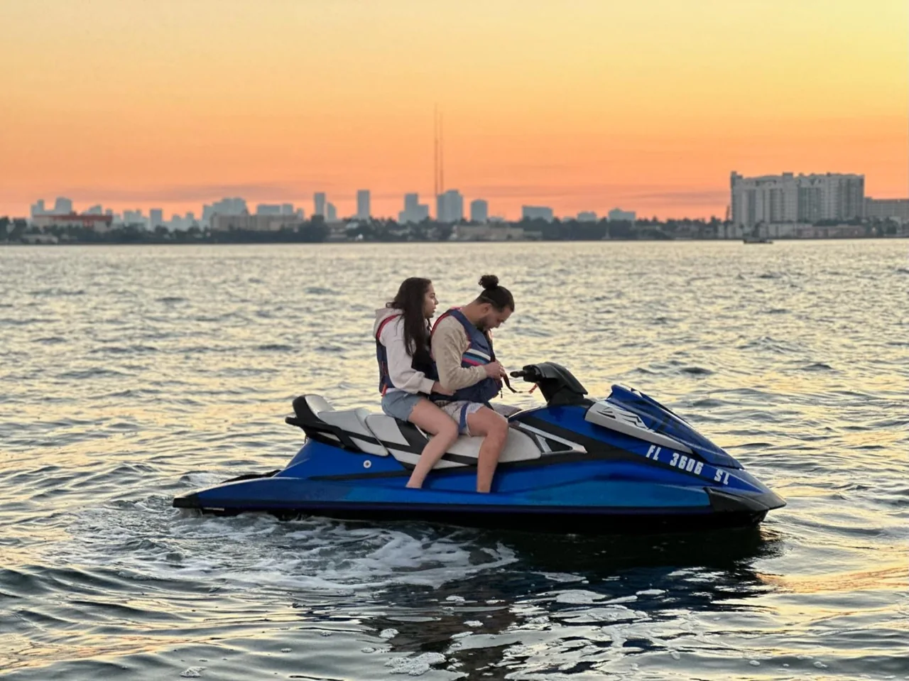 Two riders on a jet ski at sunset