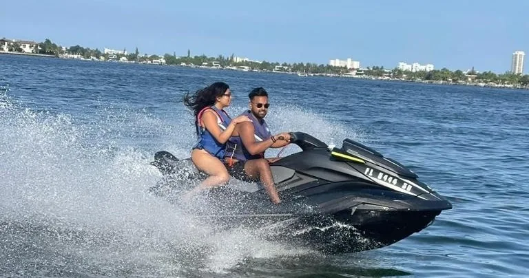 Two jet ski riders turning through a spray of water