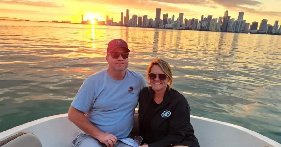 Two passengers on a boat at sunset with the Miami skyline beyond