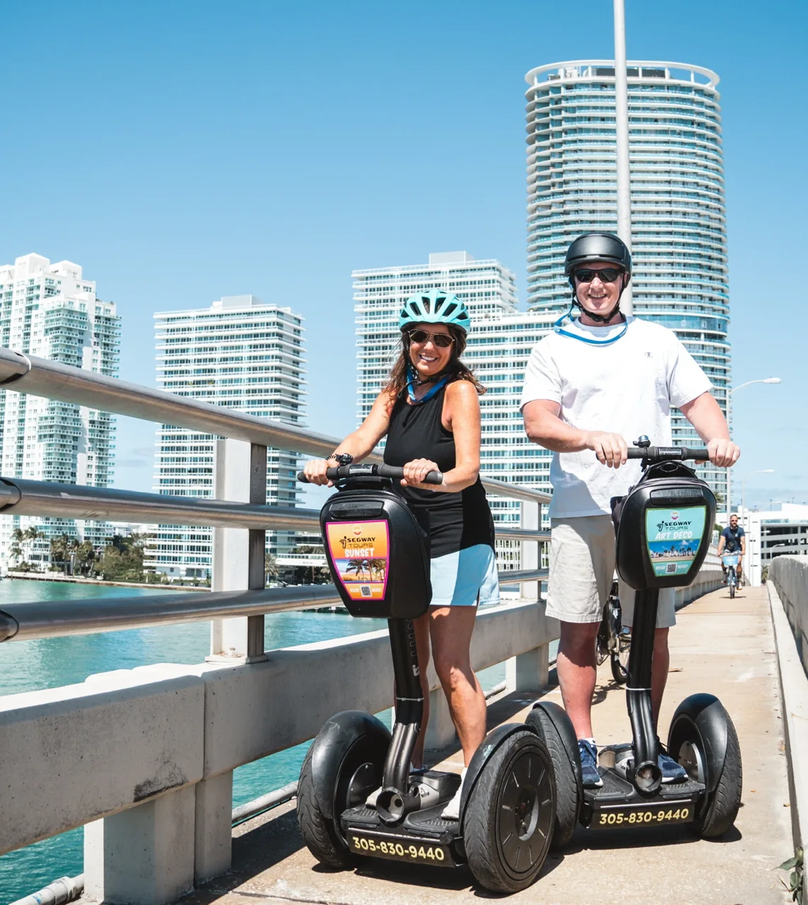 Two Segway riders beside a waterfront railing