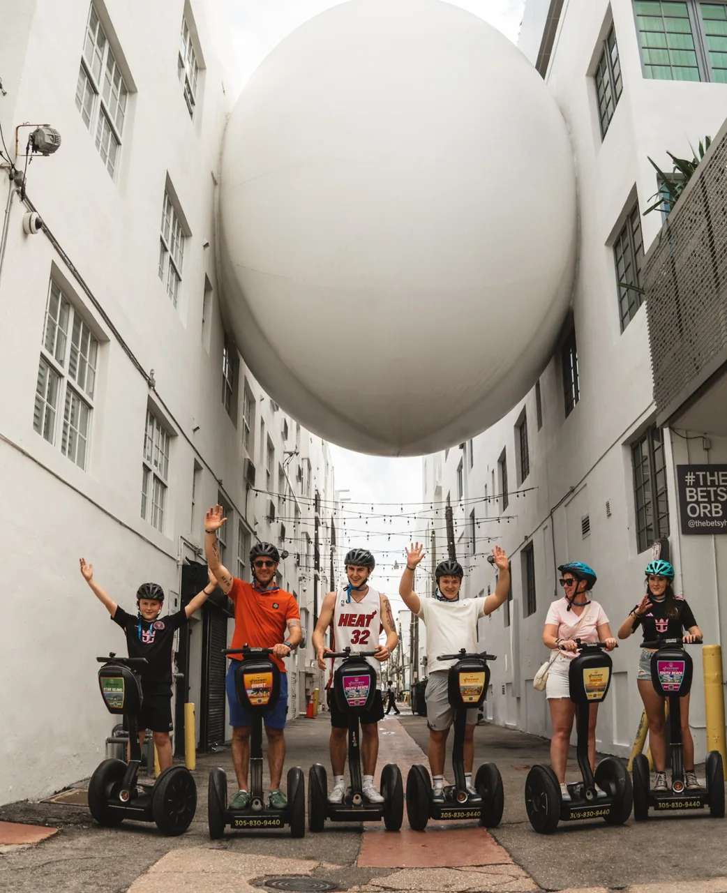 A group beneath a large outdoor spherical sculpture