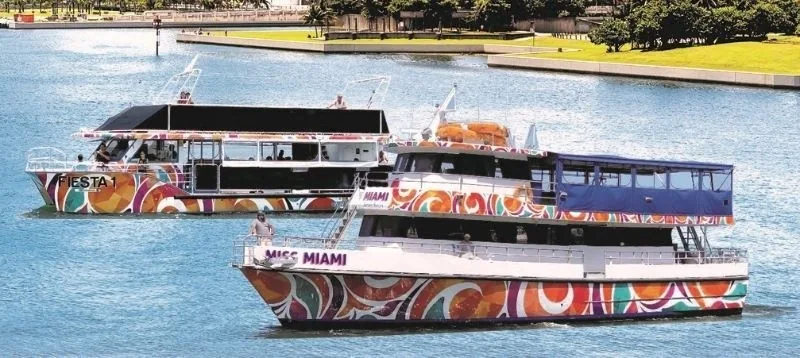 A two-deck sightseeing boat beside a marina