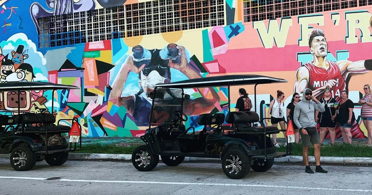 Golf carts parked beside a colorful geometric mural