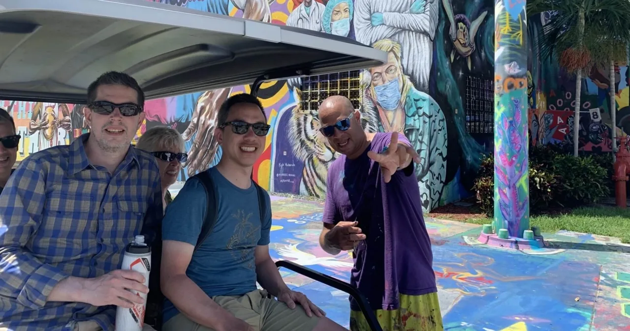 Visitors beside a golf cart on a Wynwood street